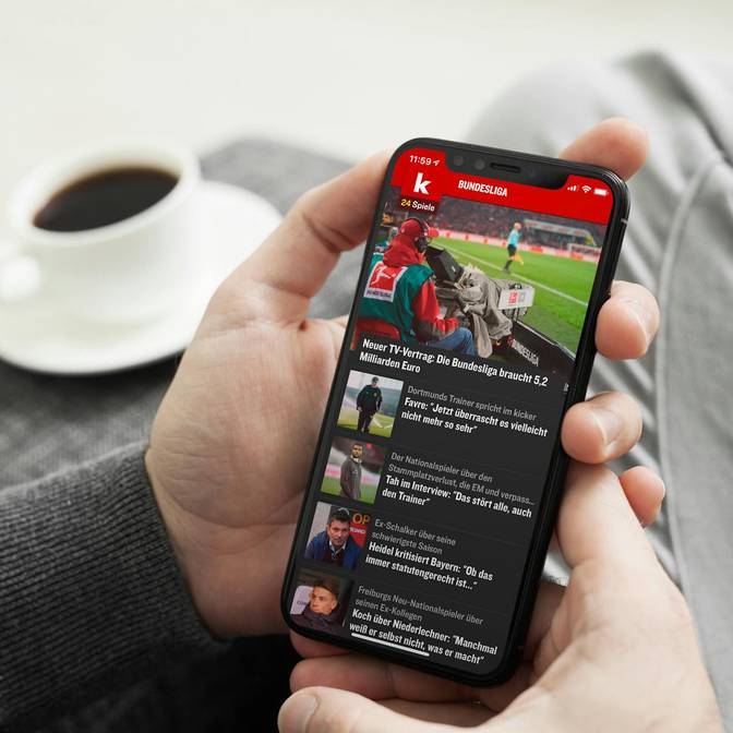 Ein Foto, das eine Person zeigt, die ein iPhone in der Hand hält, auf dem die kicker-App geöffnet ist.